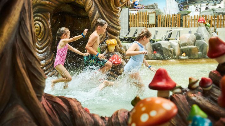 Drei Kinder hüpfen durch das flache Wasser in Trølldal