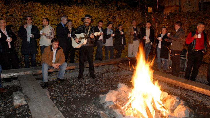 Mann spielt Gitarre am Lagerfeuer