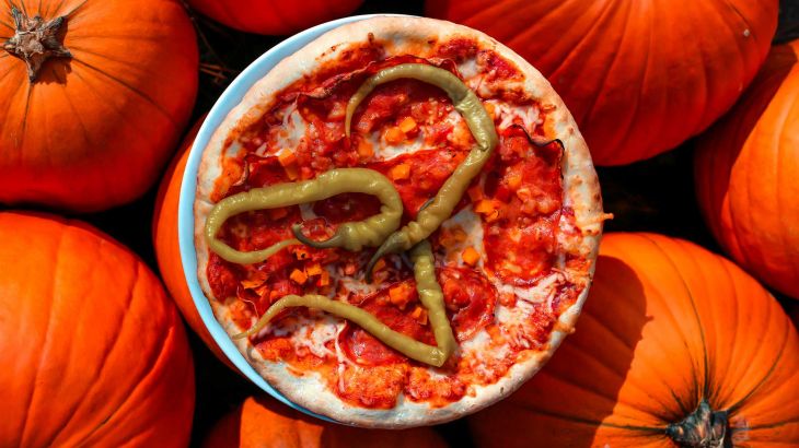 Halloween-Pizza mit Kürbissen im Hintergrund