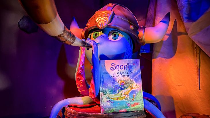 Snorri mit Horn und dem 3. Band der Bilderbuchreihe