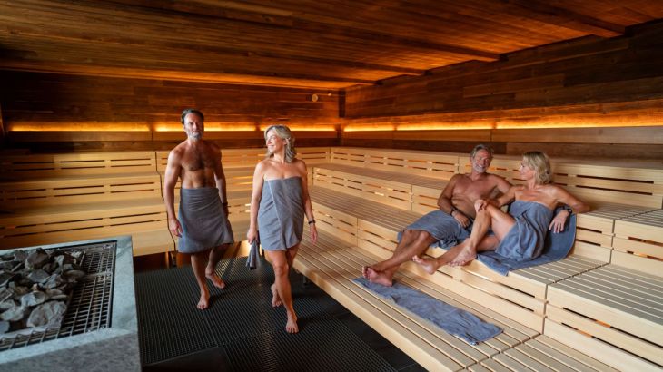 Zwei Senioren Paare sitzen in der Sauna in Rulantica Hyggedal