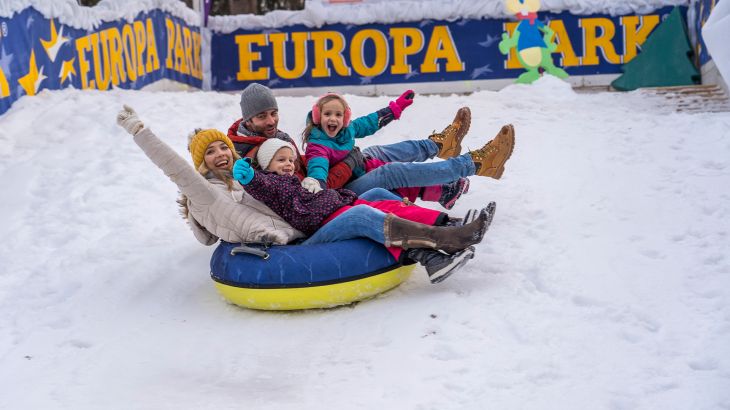 Familie rutscht zusammen den Berg herunter in den Snowtubes