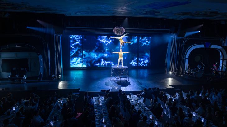 Zwei Akrobaten auf der Bühne der Dinner-Show. Der eine Akrobat balanciert mit einer Hand auf dem Kopf des anderen. 