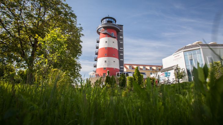 Der Leuchtturm des Hotels "Bell Rock" von außen in einer idyllischen Landschaft.