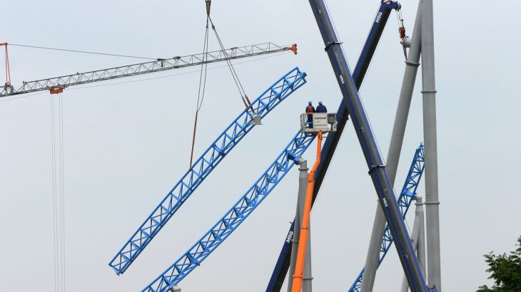 Ein Kran hebt ein Looping-Teil des blue fire Megacoaster auf die richtige Höhe zur Installation der Schiene.