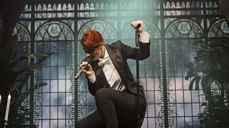 A singer in a chic suit performs on stage at Eden Manor.