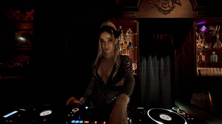 A female DJ is standing at the mixing desk in the mystically avant-garde Eden Manor theatre.