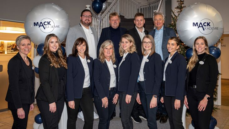 Frederik Mack und Jürgen Mack auf einem Gruppenfoto mit den freundlichen Mitarbeitenden der MACK Akademie.
