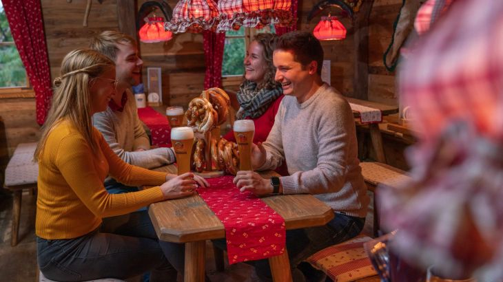 Four colleagues are spending a convivial evening in the ERDINGER Hütt'n at Europa-Park. There are pretzels and beer on the table.