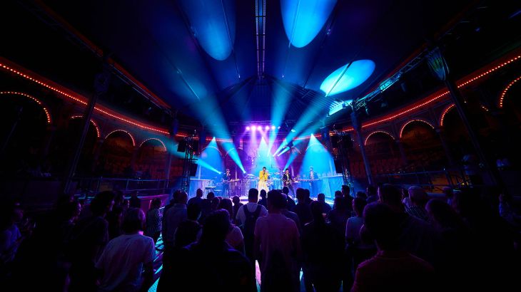 Die Band 'The Music of Queen' performt auf der Bühne der spanischen Arena in lilanem Licht.