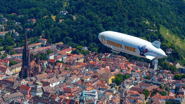 Op weg naar Rust vliegt de Europa-Park Zeppelin over de Freiburger Münster.
