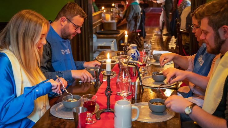 Vier Personen essen an der Tafel des Alemannischen Ritermahls.