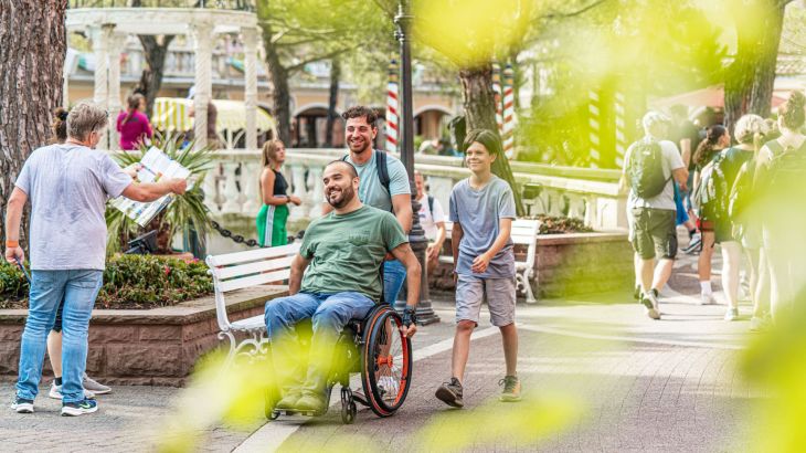 Ein Rollstuhlfahrer wird durch den italienischen Themenbereich geschoben.