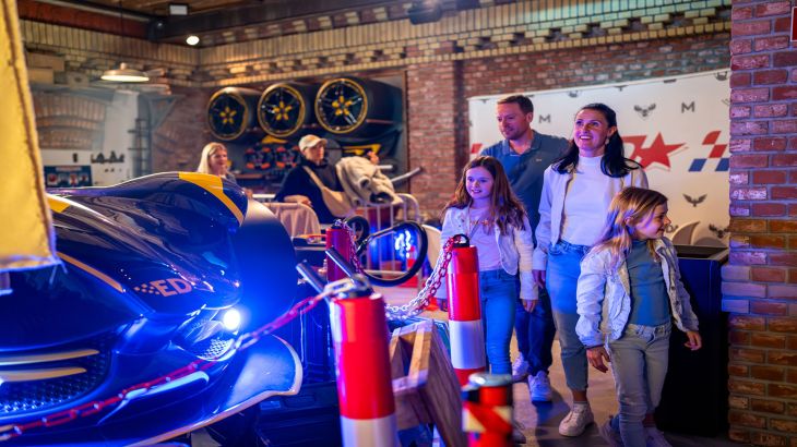 Familie erkundet zusammen den Wartebereich der Attraktion GRAND PRIX EDventure.