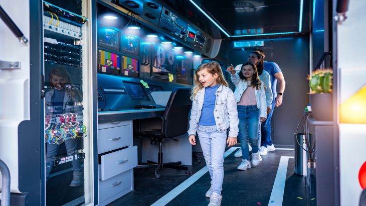 Familie geht staunened durch den Wartebereich von GRAND PRIX EDventure.