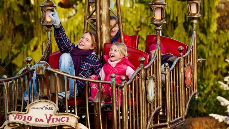Vier Kinder fahren zusammen die Attraktion Volo da Vinci im Winter.