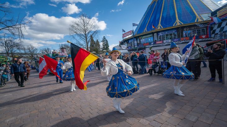 Tänzerinnen der Parade schwenken unterschiedliche Länderflaggen.