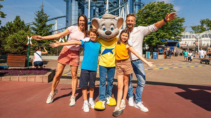 Eine Familie steht gemeinsam mit Ed Euromaus vor der Attraktion Euro-Mir im Europa-Park.