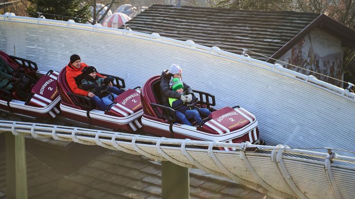 Eine Familie fährt in zwei Bobs der Schweizer Bobbahn die rasante Strecke entlang.