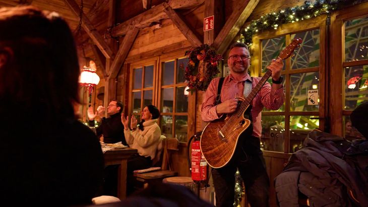 Ein Musiker in Lederhose spielt während einer Weihnachtsfeier in der Erdinger Hütte.