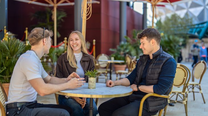 Drei Personen sitzen an einem Tisch im Außenbereich des Monegassischen Themenbereichs im Europa-Park.