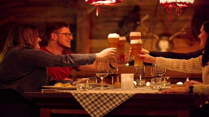 A group of friends raise a glass of wheat beer at the ERDINGER Hütt'n Evening in the Portuguese themed area of Europa-Park.