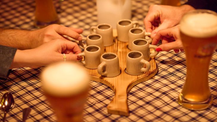A close-up of four hands reaching for shot glasses at the ERDINGER Hütt'n Evening in the Portuguese themed area of Europa-Park.