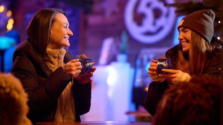 Zwei Frauen stehen mit einer Feuerzangenbowle in der Hand in der Ice Bar