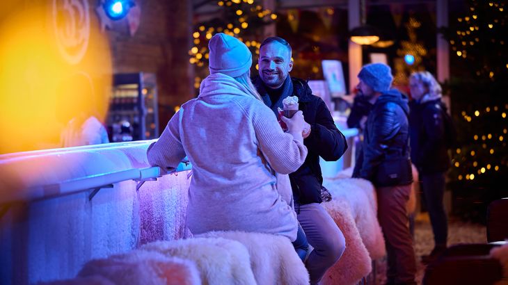 Paar sitzt an der Ice Bar in Spanien und prostet sich zu