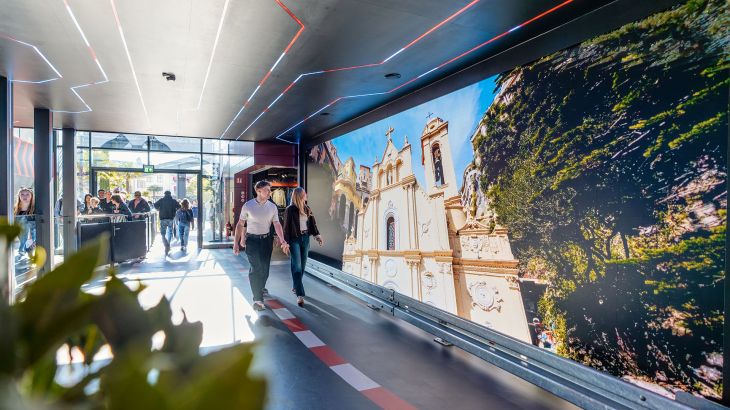 Ein Pärchen läuft durch die Ausstellung im Monegassischen Themenbereich des Europa-Park. Links sieht man die Warteschlange für die Silver Star.