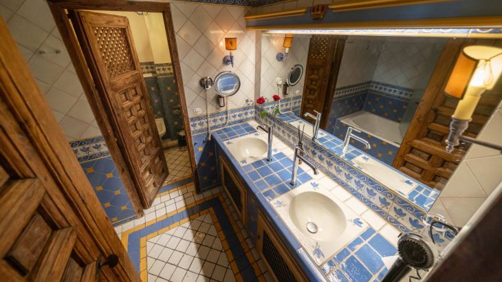 Königssuite Badezimmer rechts breiter Spiegel darunter blau weiß orange Fliesen links Holztür zur Toilette