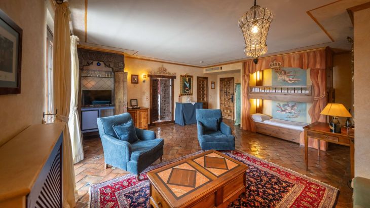 El Andaluz Königssuite Wohnraum mit Etagenbett rechts und Engelmalerei an der Wand. In der Mitte Stuhl mit Holztisch