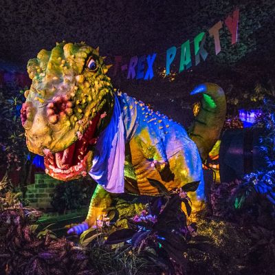 Eine T-Rex Figur, darüber hängt eine Girlande mit der Aufschrift "T-Rex Party"