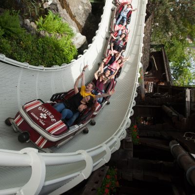 Besucher in der Kurve der Schweizer Bobbahn, sie heben ihre Hände in die Luft
