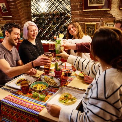 Freundesgruppe stößt gemeinsam mit Cocktails bei leckerem Essen im Restaurant Don Quichotte im Europa-Park an.