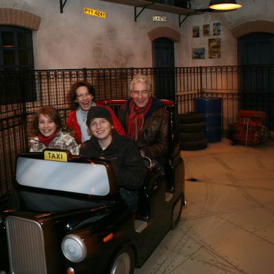 Großeltern und ihre Enkel fahren gemeinsam mit einem Taxi der Attraktion Crazy Taxi.