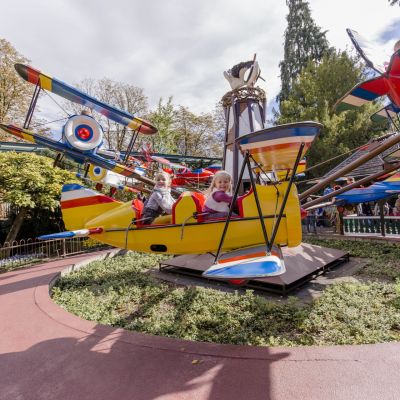 Kinder sitzen in einem Flugzeug der Attraktion Roter Baron