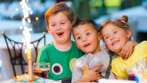 Fröhliche Kinder vor einem Geburtstagskuchen