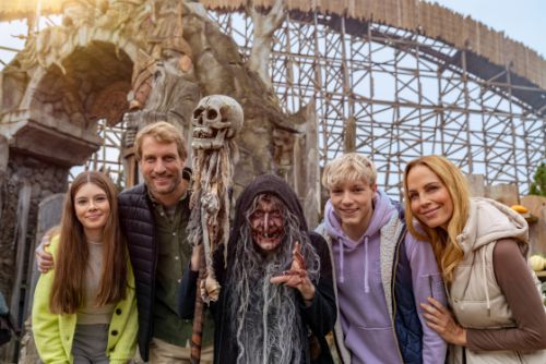 Familie mit zwei Kindern vor der Attraktion WODAN - Timburcoaster. In der Mitter eine Hexe