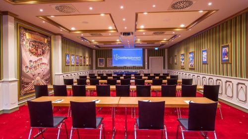 Sicht auf mehrere Stuhlreihen im Meetingraum Circus Celebration mit Leinwand im Hintergrund
