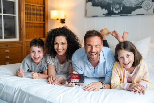 Eine Familie auf dem Bett mit der Hotel Friends App