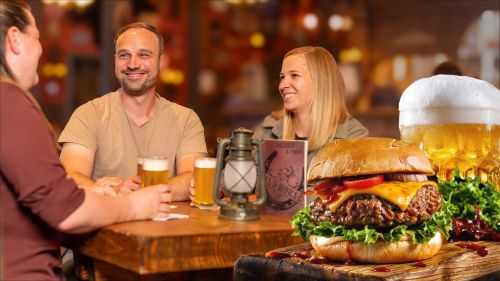 Drei Personen sitzen lachend an einem Tisch auf dem drei gefüllte Bierkrüge stehen. Im Vordergrund ist ein Burger und Bier abgebildet.