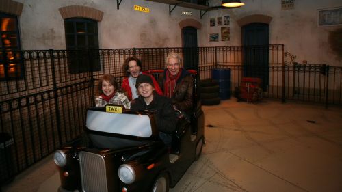 Großeltern und ihre Enkel fahren gemeinsam mit einem Taxi der Attraktion Crazy Taxi.