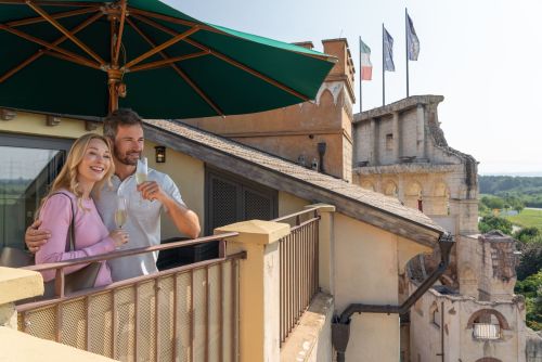 Lächelndes Pärchen mit Champagner auf dem Balkon