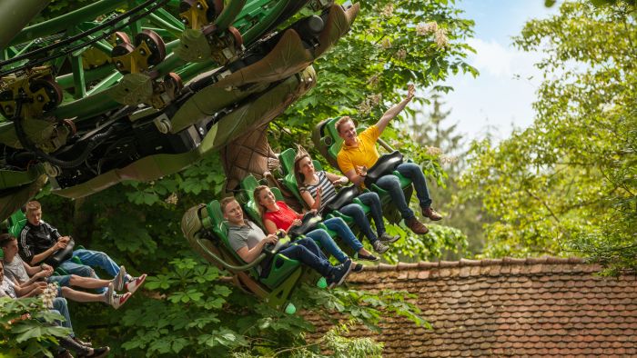Besucher genießen die Fahrt der neuen Attraktion durch grüne Landschaften.
