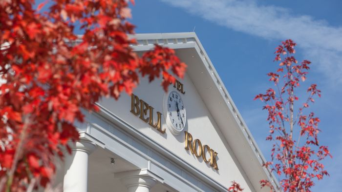 Eingang von dem Hotel "Bell Rock" mit roten Bäumen umrandet.