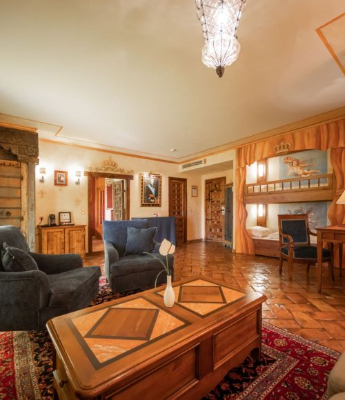 Wohnraum Königssuite links zwei dunkelblaue Sessel und auf der rechten Seite das Etagenbett mit Holzverkleidung