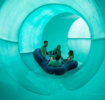 Besucher rutschen im Reifen durch eine Röhre