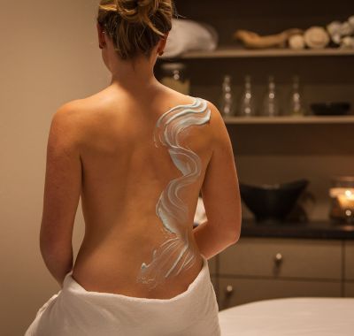 Frau mit Pflegecreme auf dem Rücken