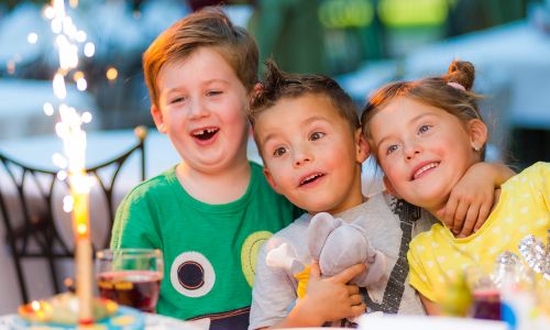 Kindergeburtstag im Camp Resort (Übernachten) Fröhliche Kinder vor einem Geburtstagskuchen